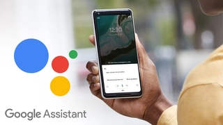 Hand hält ein Smartphone, links daneben das Google-Assistant-Logo