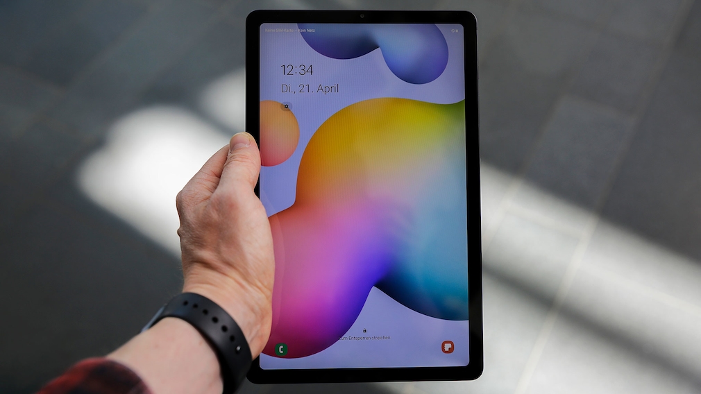 Hand holds the Galaxy Tab S6 Lite, the screen is on.