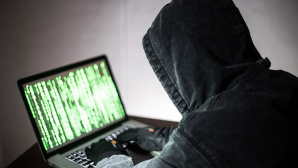 Hacker vor Laptop mit Programmiercode © gettyimages.de / krisanapong detraphiphat