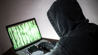 Hacker vor Laptop mit Programmiercode