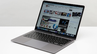 Das MacBook Air 2020 steht auf einem weißen Tisch vor einer grauen Wand.