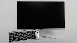 Medion Akoya E27401 vor grauem Hintergrund. Maus und Tastatur lehnen am PC.