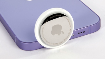 Apple AirTag lehnt an einem iPhone 12