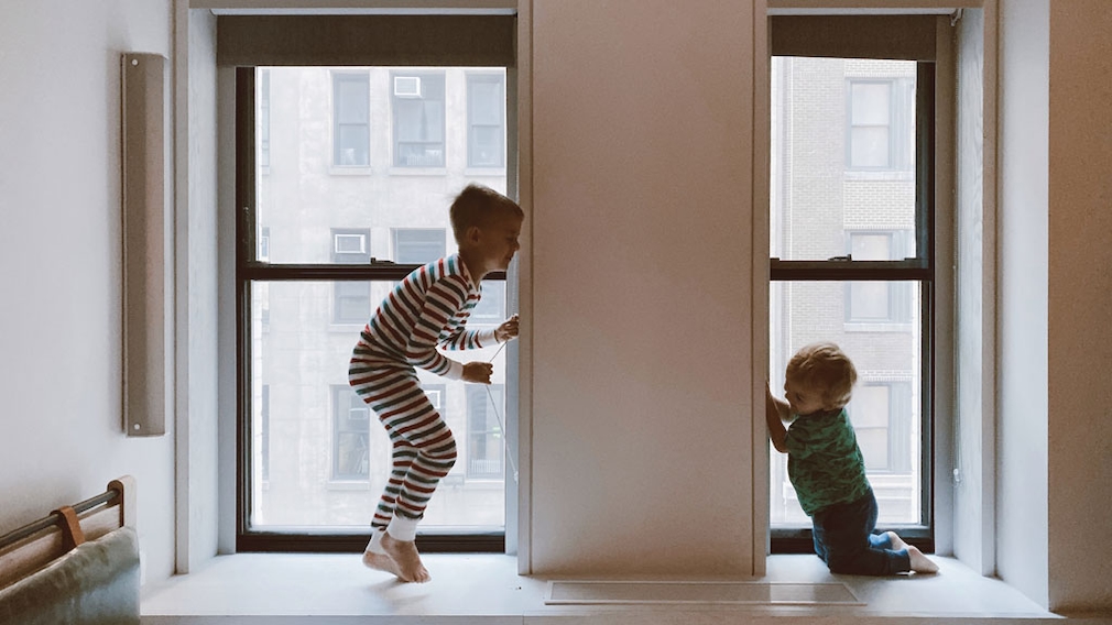 Zwei hüpfende Kinder auf Fensterbank