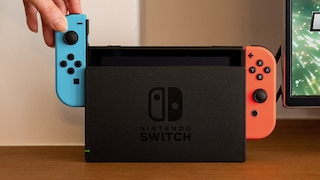 Hand schiebt blauen Joy-Con in die Nintendo Switch.