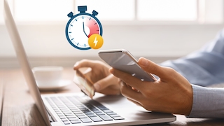 Männerhände halten Handy und Kreditkarte vor einem Laptop, Stopuhr-Icon darüber