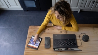 Eine Frau sitzt mit Tablet und Laptop am Schreibtisch