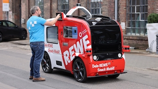 Rewe-Lieferservice-Wagen in Wohngebiet, Fahrer liefert Kiste aus