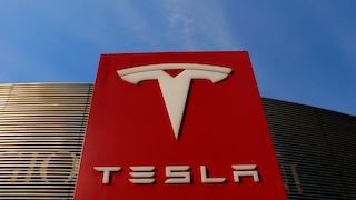 Säule mit Tesla-Logo vor blauem Himmel