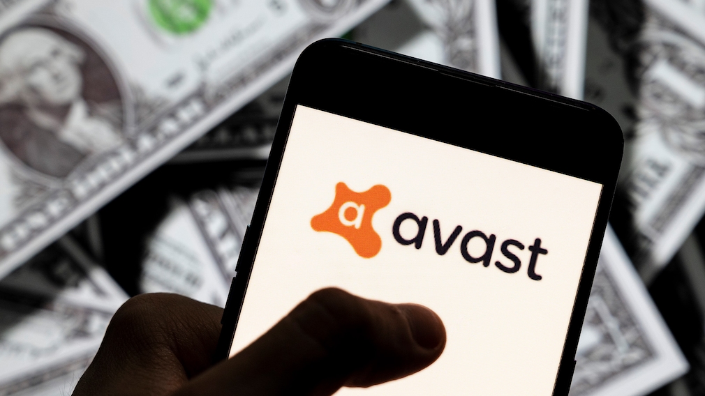 Hand hält Smartphone mit Avast-Logo über einen Haufen Geldscheineö