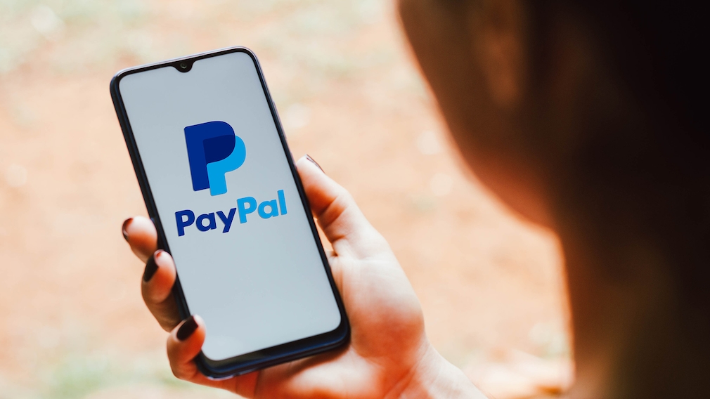 Das PayPal Logo auf in der Hand gehaltenem Smartphone