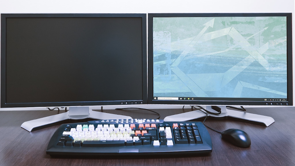 Tastatur und Maus vor zwei Monitoren