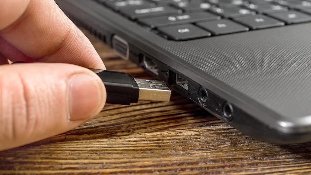 Person schließt USB Gerät an einen Laptop an 