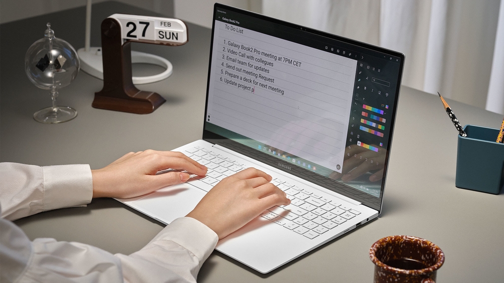 Hands typing on a notebook.