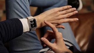 Finger zeigt auf eine Smartwatch am Handgelenk.