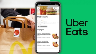 McDonald’s-Papiertüte neben Smartphone und Logo von Uber Eats