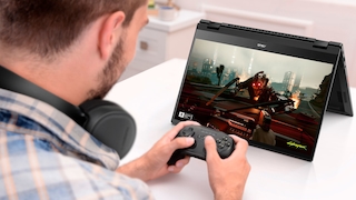 Ein Mann spielt ein Videospiel mit einem Controller auf einem Notebook.