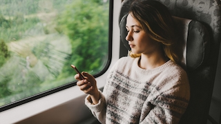 Eine Frau benutzt ein Smartphone in einem Zug.