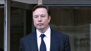 Der Unternehmer Elon Musk in einem Anzug mit Krawatte.