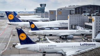Lufthansa-Flugzeuge stehen an einem Flughafen an Gates.