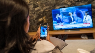 Eine Person überträgt den Handybildschirm-Inhalt auf einen Fernseher