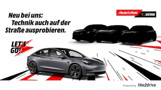 Tesla und drei nicht näher gezeigte Autos neben Saturn- und Media-Markt-Logo