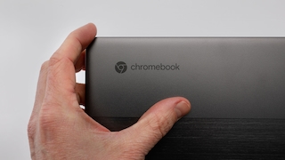 Eine Hand hält ein Chromebook, das Logo ist im Fokus.
