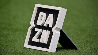 Ein DAZN-Logo steht auf einem Rasenplatz.