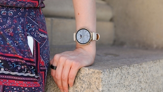 Huawei Watch GT 4 am Handgelenk einer Frau, die sich auf einem Stein abstützt. 