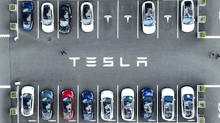 Viele Teslas stehen auf einem Parkplatz. 