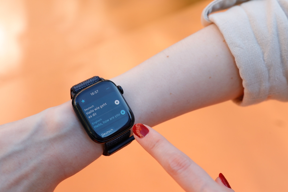 Apple Watch 10 am Handgelenk einer Person. Auf dem Display ist die Übersetzung eines Satzes vom Deutschen ins Englische zu sehen.