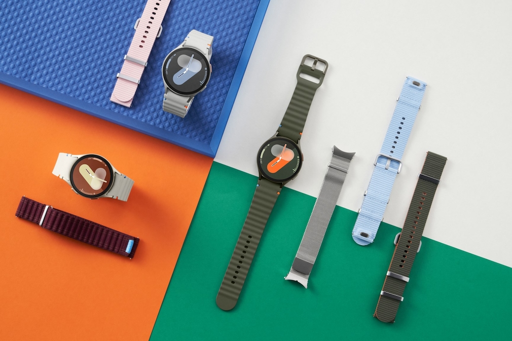 Galaxy Watch 7 und ihre Armbänder in diversen Farben auf einem Untergrund in blau, weiß, orange und grün.