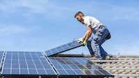 Person installiert Solarmodule auf Dach