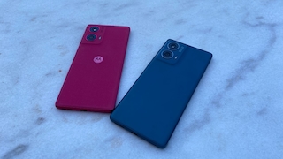Motorola Edge 50 Fusion in Peacock Pink und Ballad Blue mit der Rückseite nach oben auf einer marmorierten Oberfläche liegend