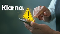Eine Person tippt auf ihr Handy, darüber ein Warndreieck und das Klarna-Logo.