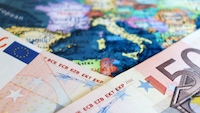 Zwei 50 Euro-Scheine auf einer Weltkarte