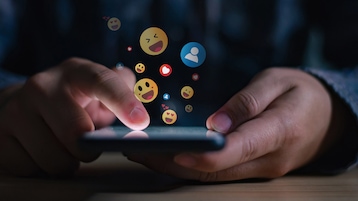 Person tippt auf Handy Emojis ein