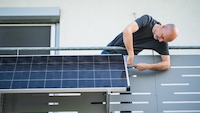 Mann installiert Solarmodul an einem Balkon
