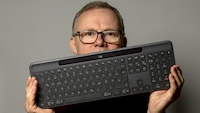 Testredakteur Sven Schulz hält die Tastatur Logitech Signature Slim Solar+ K980 vor sein Gesicht in die Kamera.