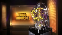 Lotterie-Trommel für die Eurojackpot-Ziehung mit den Gewinnkugeln und Eurojackpot-Schriftzug im Hintergrund