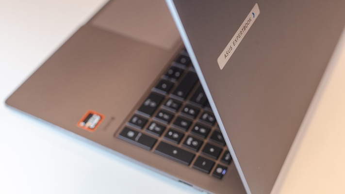 Schräg von oben aufgenommenes, teilweise geöffnetes Asus ExpertBook PM3606CKA in grauem Gehäuse, sichtbar sind ein Teil der schwarzen Tastatur, das Touchpad und der aufgeklappte Displaydeckel mit Asus ExpertBook Schriftzug.