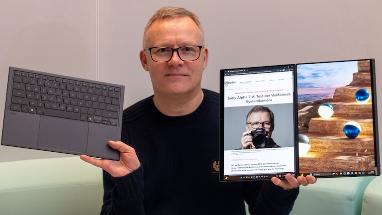 Testredakteur Sven Schulz hält das Asus Zenbook 14 Duo OLED in die Kamera – links die abnehmbare Tastatur, rechts das aufgeklappte Doppel-Display.
