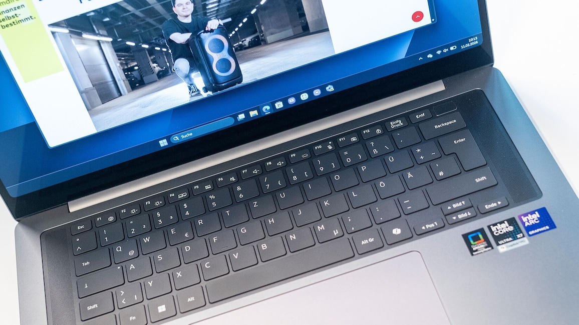 Nahaufnahme eines geöffneten Samsung Galaxy Book6 Pro. Sichtbar sind die Tastatur, das Touchpad, ein Teil des Bildschirmrahmens sowie die am rechten Rand angebrachten Aufkleber mit technischen Angaben. Auf dem Display ist eine geöffnete Website mit einem großen tragbaren Lautsprecher zu sehen.