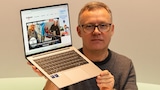 Testredakteur Sven Schulz hält das Geekom GeekBook X14 Pro mit aufgeklapptem Display hoch.