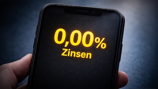 Eine Hand hält ein Smartphone, auf dessen Display in gelber Schrift „0,00 % Zinsen“ steht.