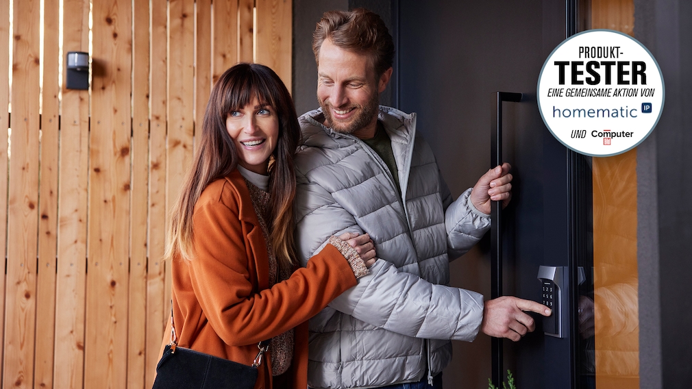 Ein Paar schließt die Haustür auf und schaut dabei nach hinten.