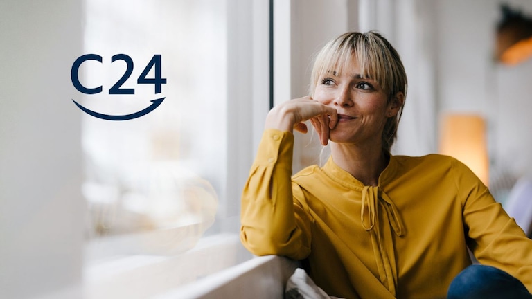 Eine Frau sitzt am Fenster und blickt nach draußen, links daneben ist das Logo „C24“ zu sehen.