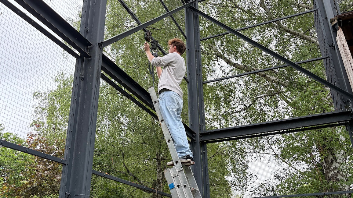 Wildkamera wird mit einem Gurt an einem Metallrahmen im Freien befestigt.