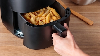 Schwarzer Airfryer mit Pommes wird geöffnet