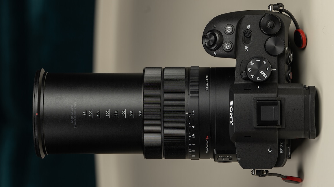 Die Sony Cyber-shot RX10 V von oben mit ausgefahrenem Zoom vor schwarzweißen Hintergrund.
